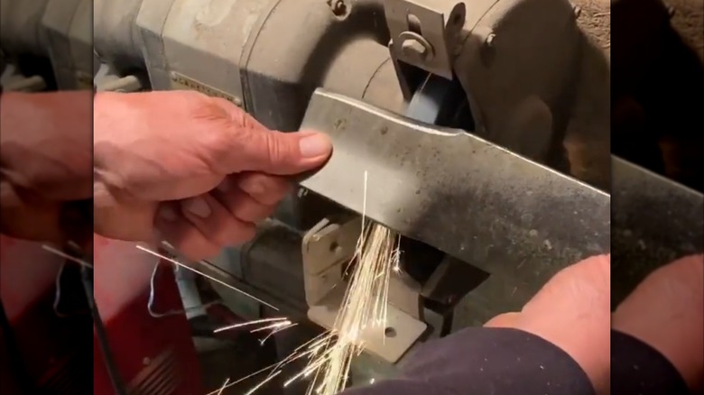 Man sharpening a blade on a bench grinder