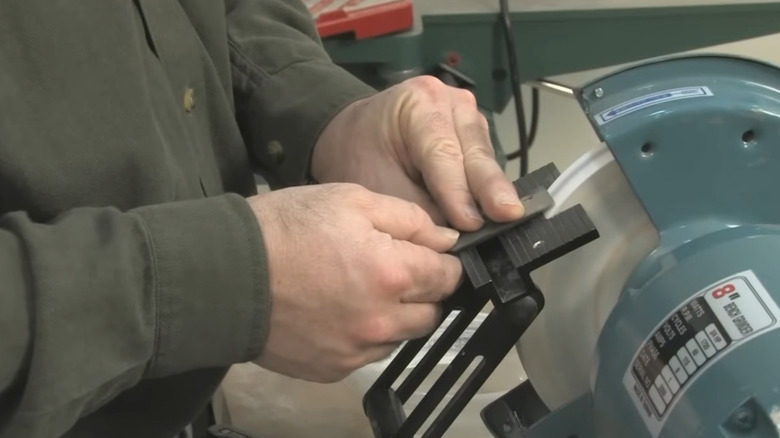 Person sharpening chisel on a bench grinder