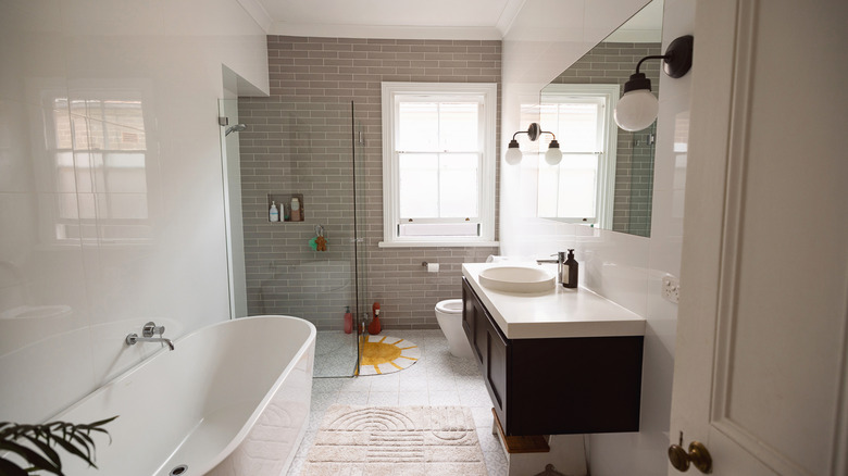Inside a bathroom with frameless shower doors, natural light, and a modern tub
