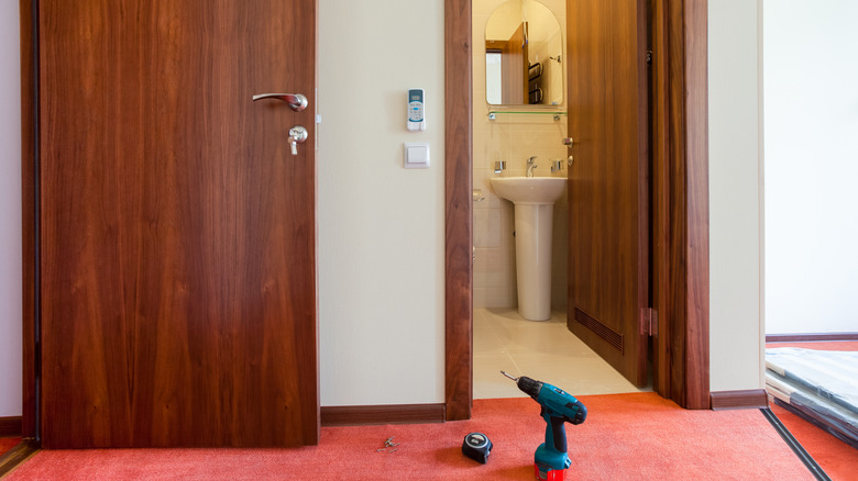 A small bathroom with inward opening door next to main door in apartment