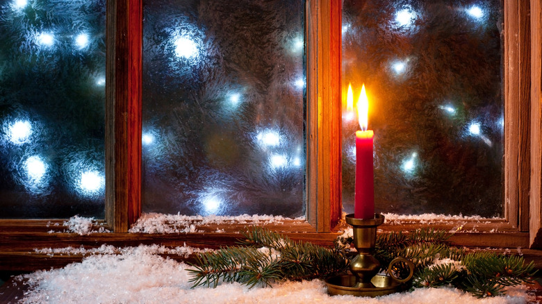 A red candle placed amidst other Christmas decorations