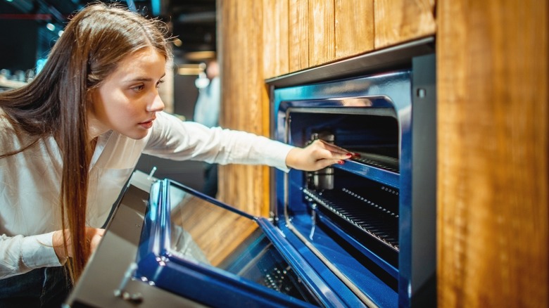 Woman opening a porcelain enamel-lined blue wall oven