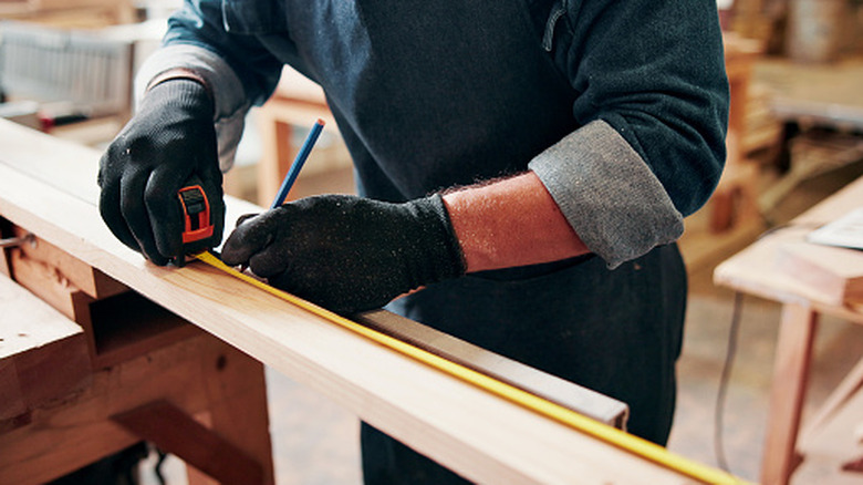 Carpenter making a marking using measuring tape