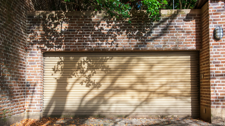 garage door on brick building, shaded by tree