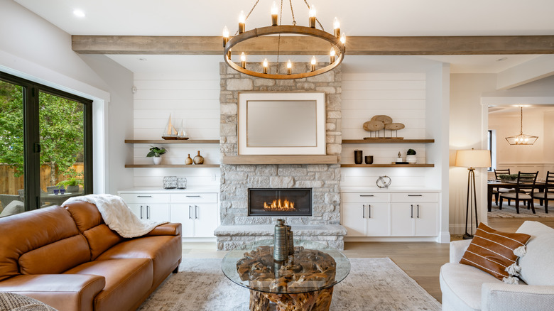 living room with stone fireplace surrounded by built-in shelving