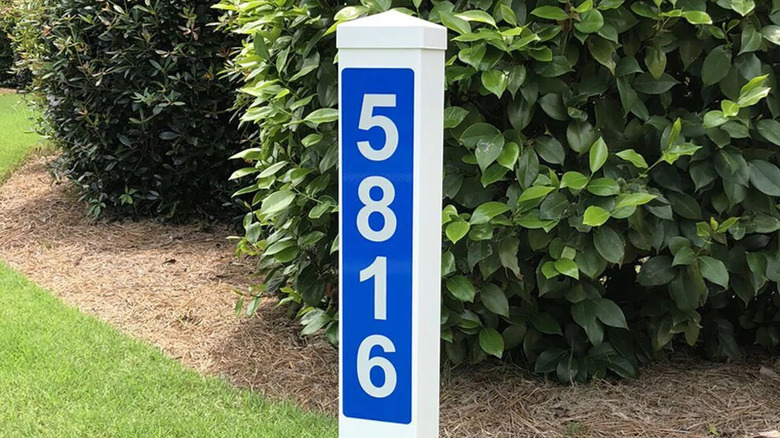 Blue numbers are on white post in yard.