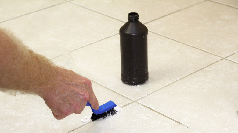 Person cleaning floor tile grout with hydrogen peroxide