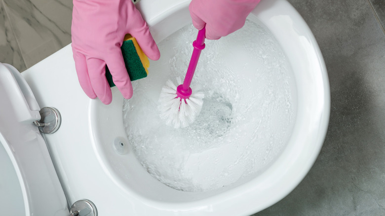 Gloves in pink hands cleaning toilet