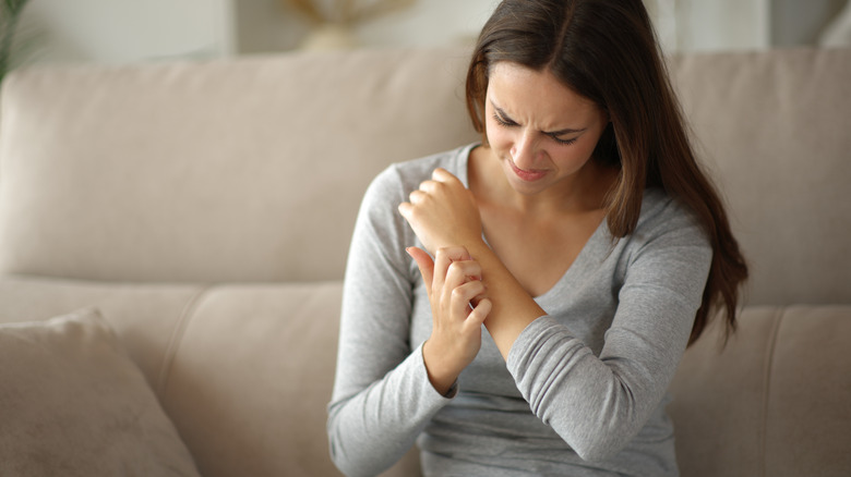 A distressed woman is scratching her arm