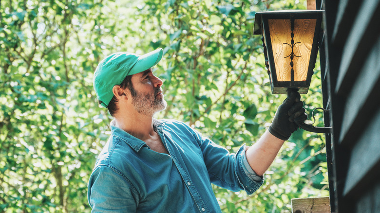 A professional inspecting a porch light