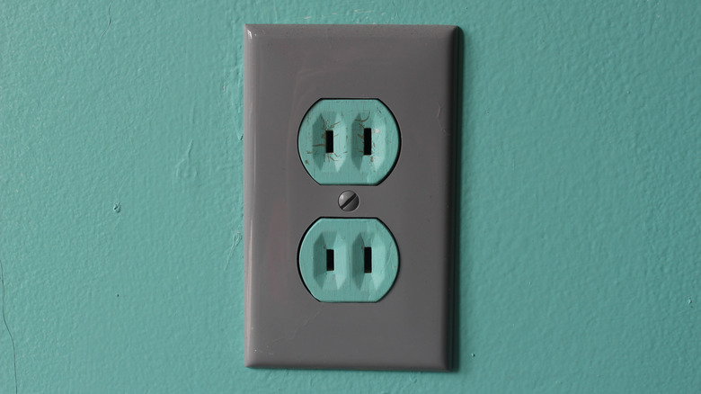 Two-pronged polarized outlet on a teal wall