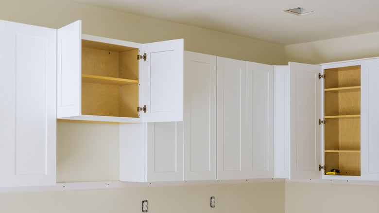 white cabinets, some with open doors, that show space at the top to the ceiling