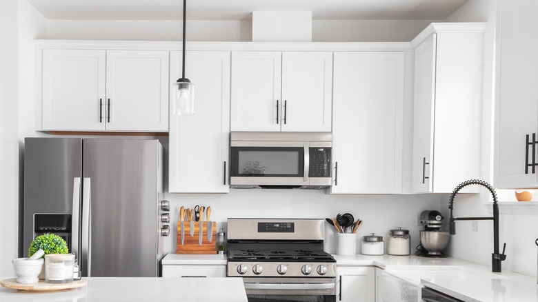 white kitchen with stainless steel appliances and gap between cabinet and ceiling