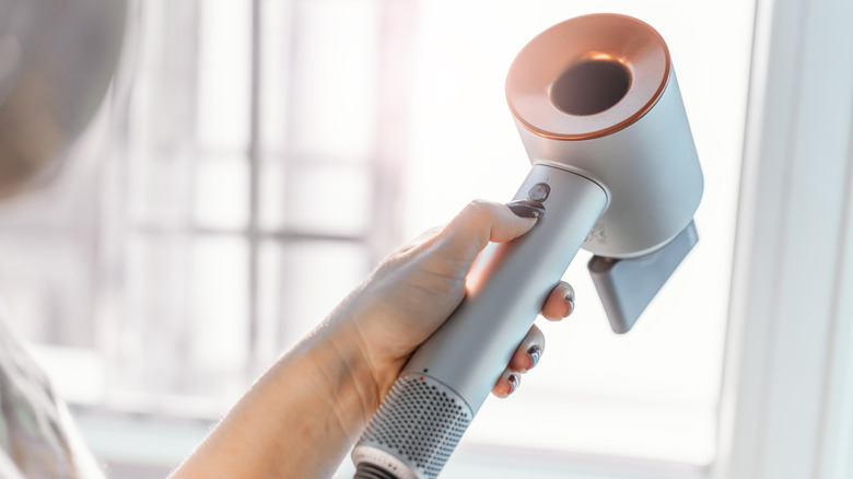 a woman switches on a hairdryer