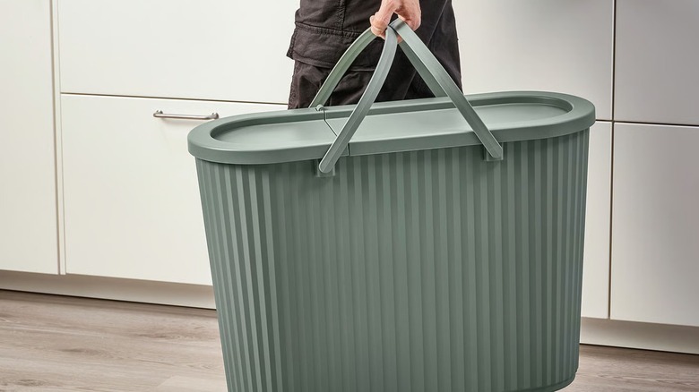 Person carrying large DAMMÄNG Bin with lid in modern