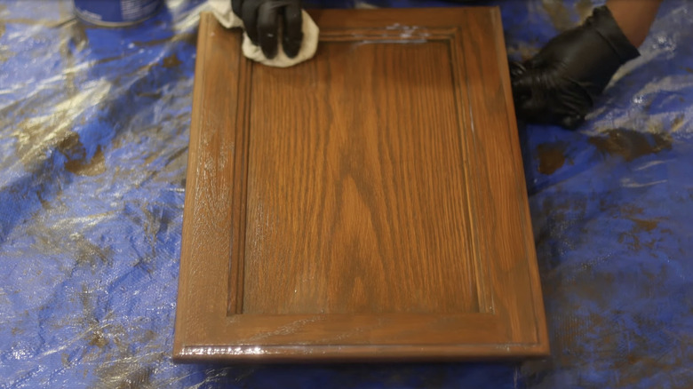 Person applying a wood stain to an oak cabinet door