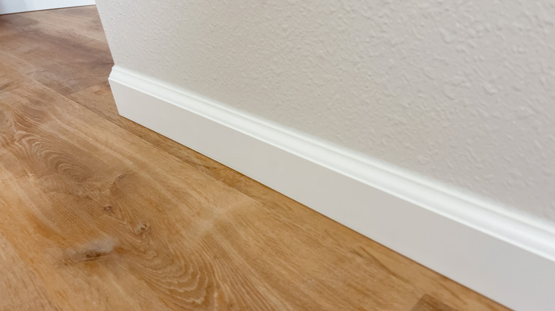 White baseboard running along a honey-colored wood floor