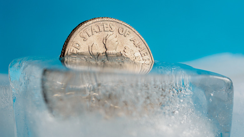 A dime half frozen in an in ice cube.