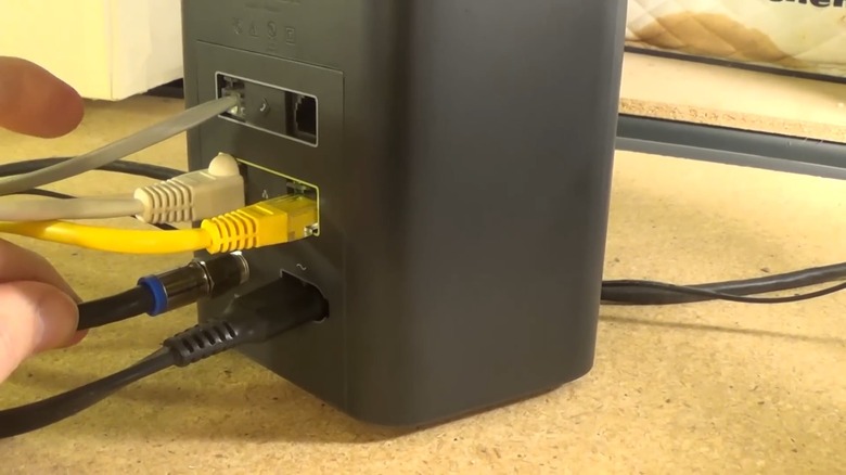 Hand checking the cables connected to an Xfinity modem