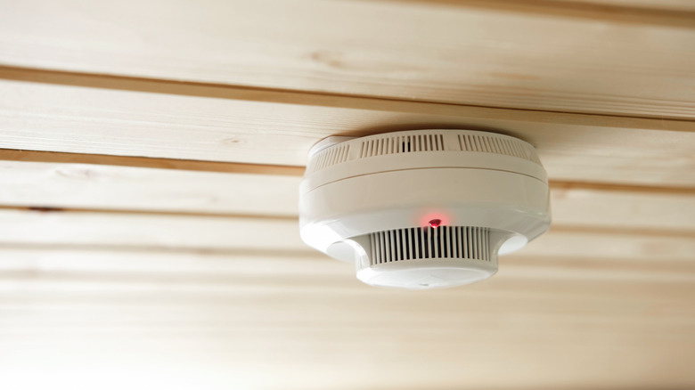 A fire alarm on a wooden ceiling with a red light
