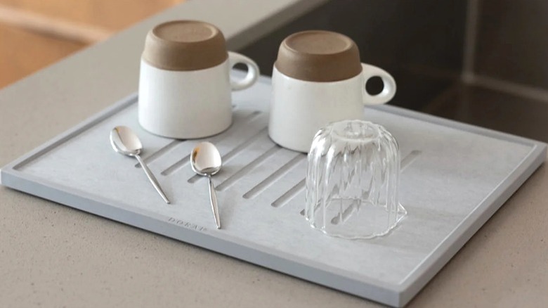 A gray stone dish drying mat with clean dishes on top