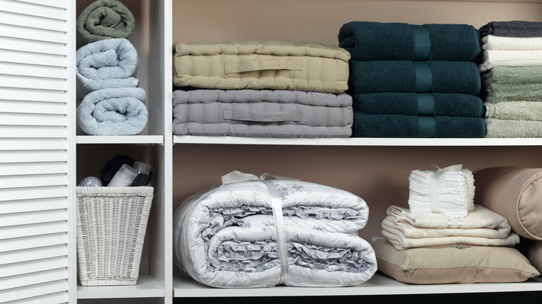 Towels and bedding stacked neatly on the shelves of a linen closet