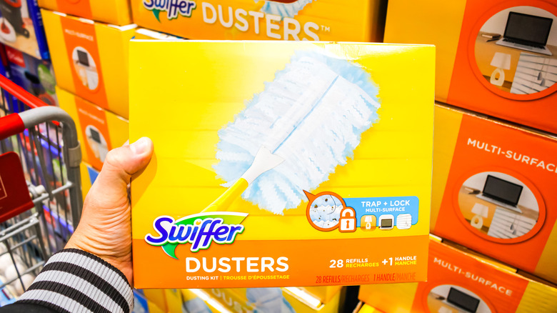 A hand holding a Swiffer duster box in a store