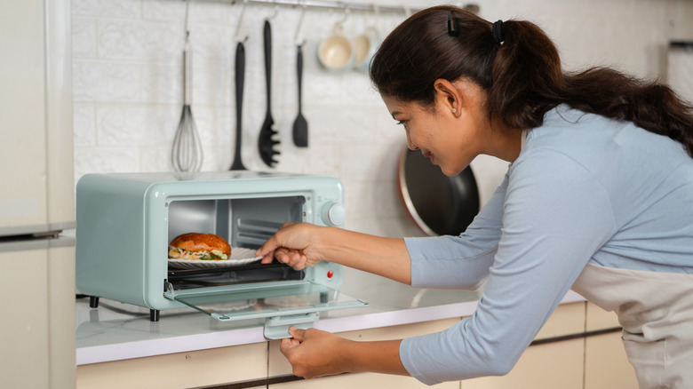 Female chef putting food in toaster oven