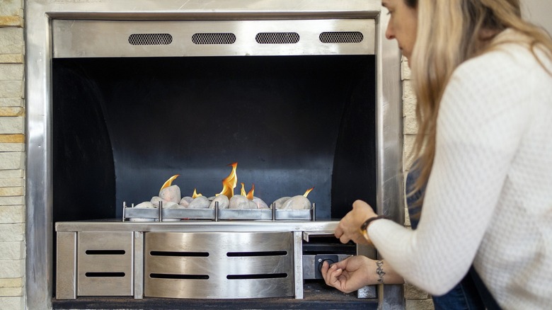 Woman adjusting the controls on a gas fireplace