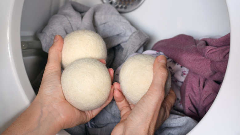 A person adds wool dryer balls to a load of laundry