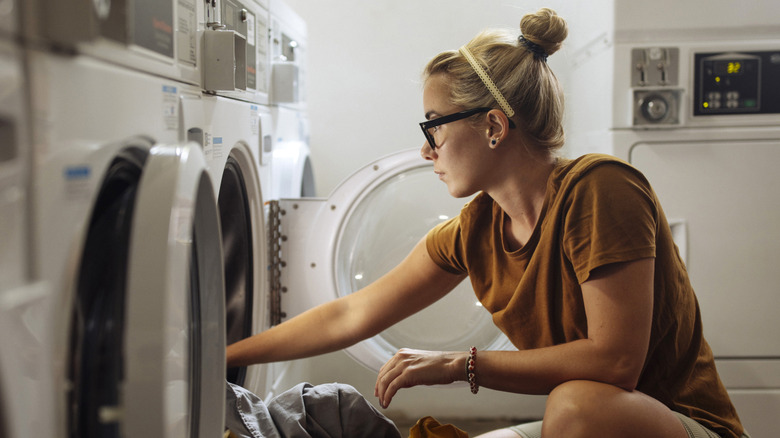 A woman reaches into a washing machine