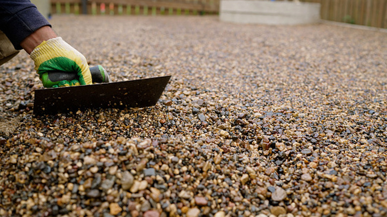 Person leveling rocks across a gravel driveway
