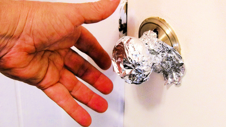 doorknob with aluminum foil and a man's hand
