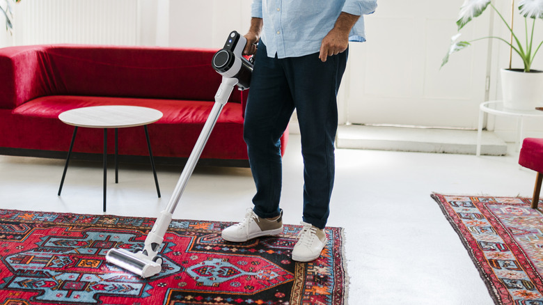 a man cleans with a cordless stick vacuum
