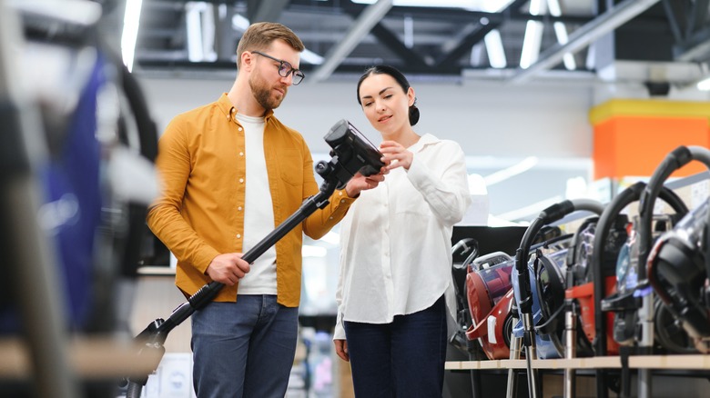 a couple looks at vacuums at a store
