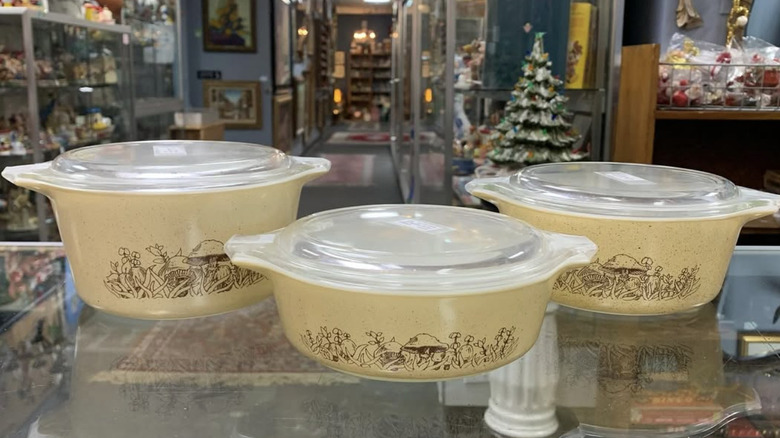 Three "Forest Fancies" Pyrex casserole dishes with lids in a vintage store