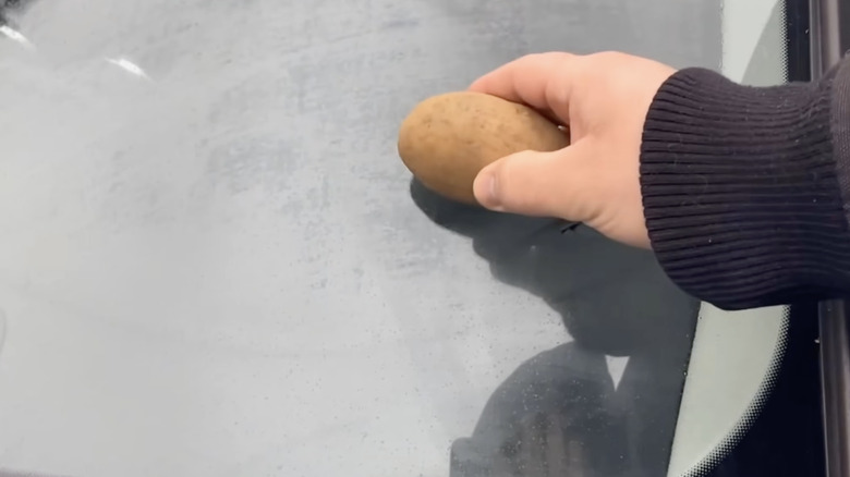 Person cleaning glass with potato