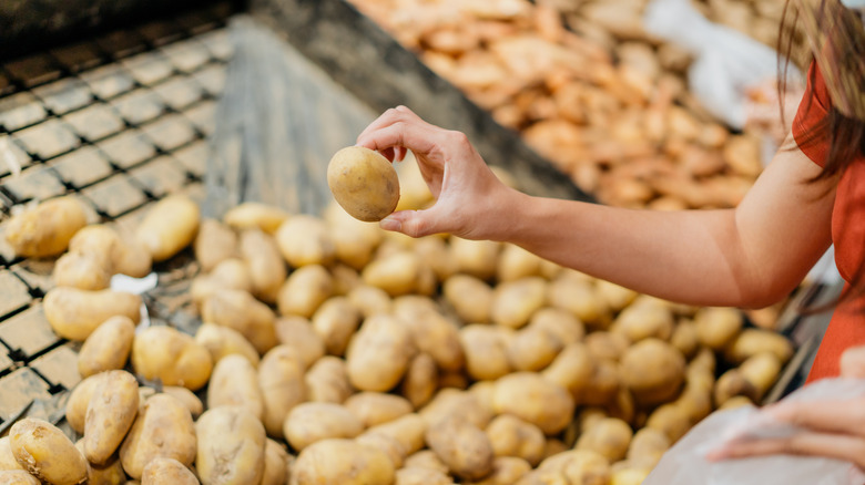Person buying raw potato in the supermarket