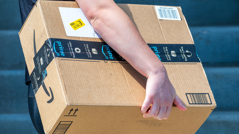 a delivery driver carries an Amazon parcel