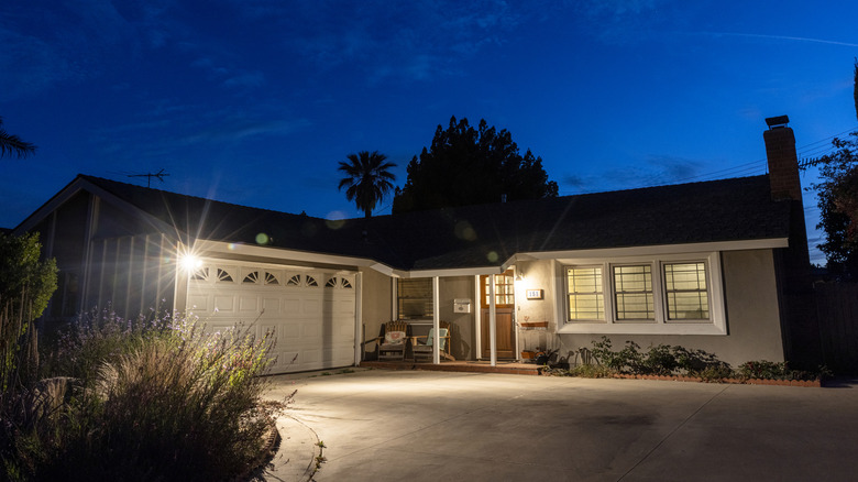 A one story home at night with the porch lights on