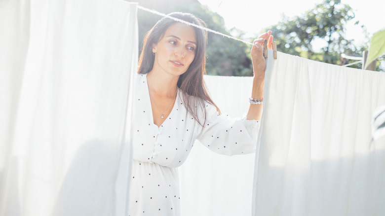 Woman hanging white sheets on a clothes line