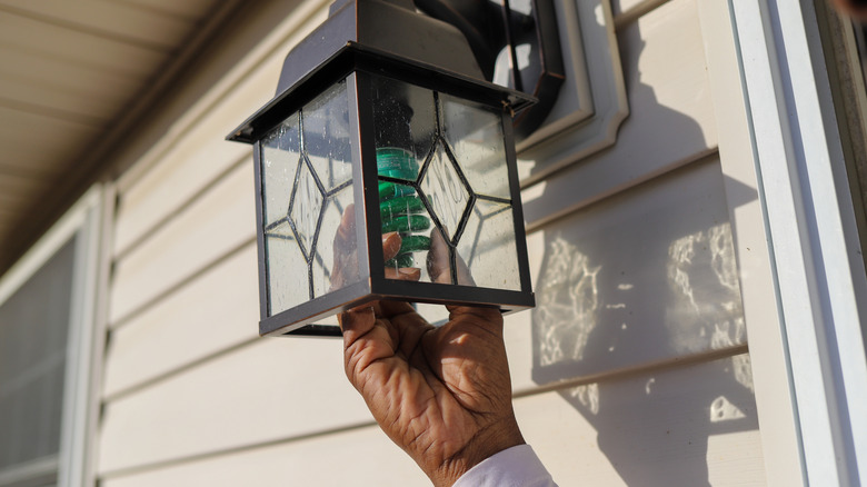 Hand changing out porch light bulb