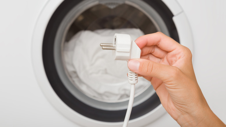 A person holding a plug in front of a dryer