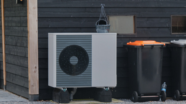 A heat pump mounted on the side of a garage