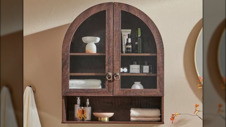 A Brown Sincido Arched Wall Cabinet installed on a bathroom wall.