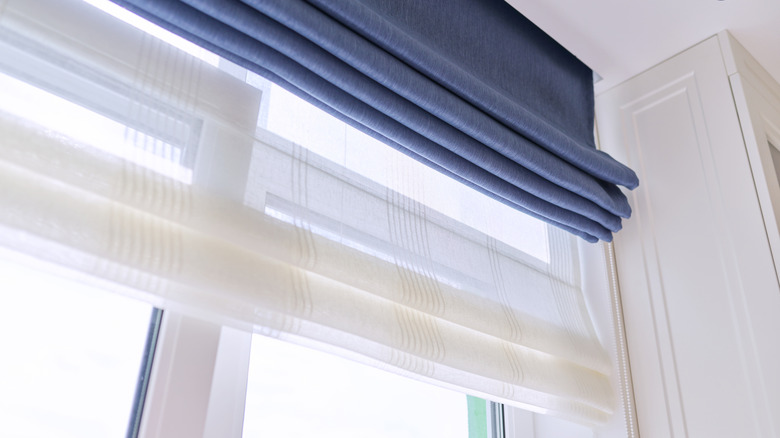 Layered roman shades with sheer white and blue roman blinds