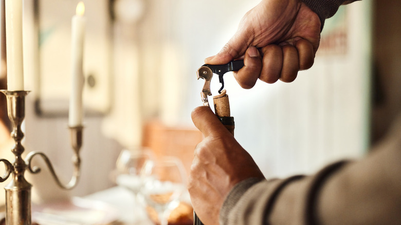 A close-up shot of a person opening a wine bottle