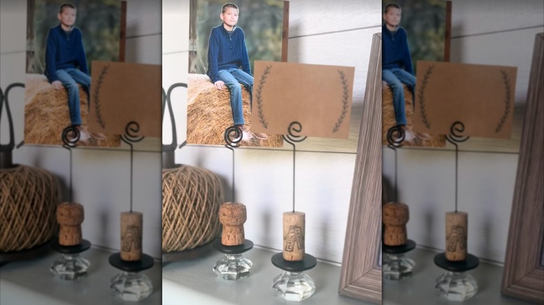 Two DIY spiral photo displays made from old wine corks and thrifted door knobs sit on a white shelf