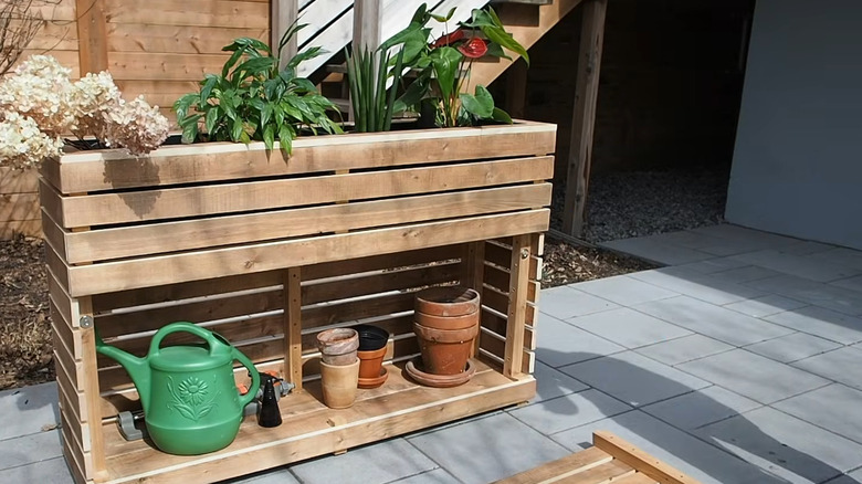 DIYer removing the front panel of a storage planter made from wood planks