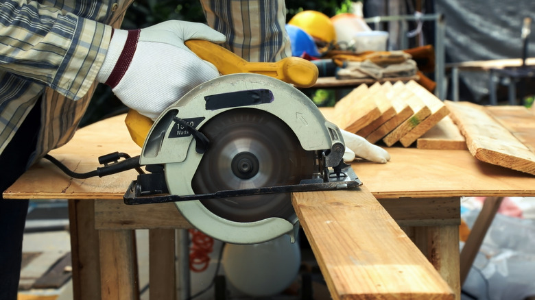 Person cutting boards with a saw in a workshop